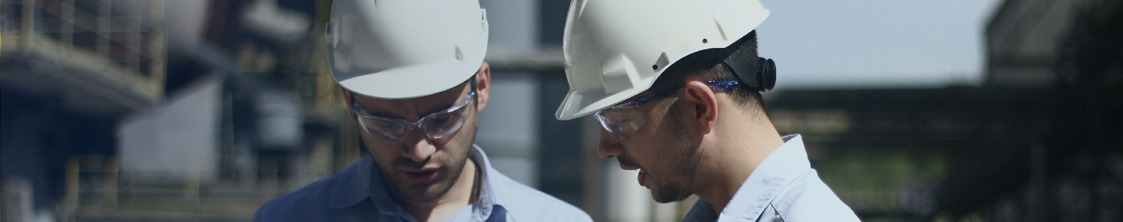 Health and safety header: two TITAN employees discussing, wearing protective equipment, helmet and glasses in Sharrcem cement plant