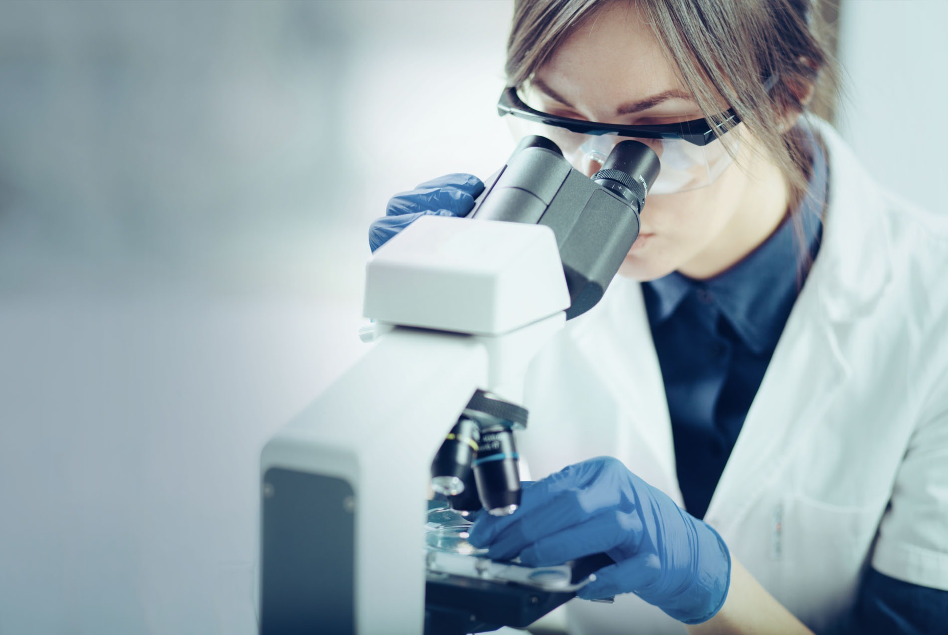 TITAN Research and Development: A woman scientist looking into a microscope TITAN Research and Development: A woman scientist looking into a microscope