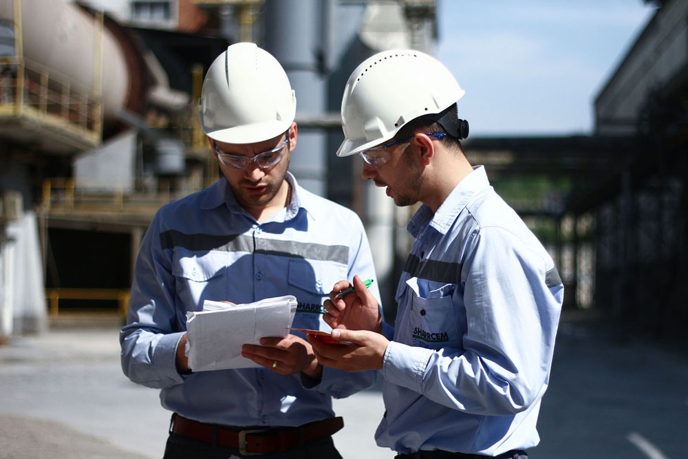 Two TITAN employees wearing protective equipment running a checking list in the plant