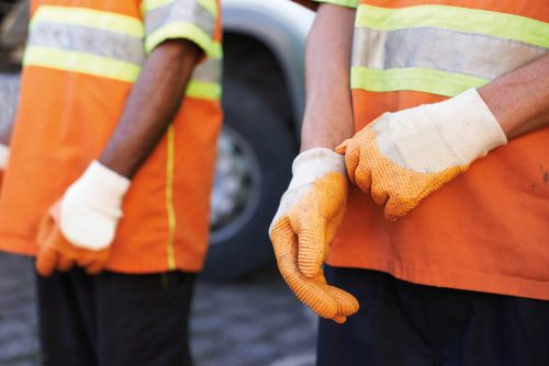 Two workers in orange suits wearing gloves to illustrate TITAN's case study on supporting the neighboring community in Alexandria initiative: